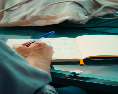 A person checking a notebook with a simple pen planning their day calmly in a bright space