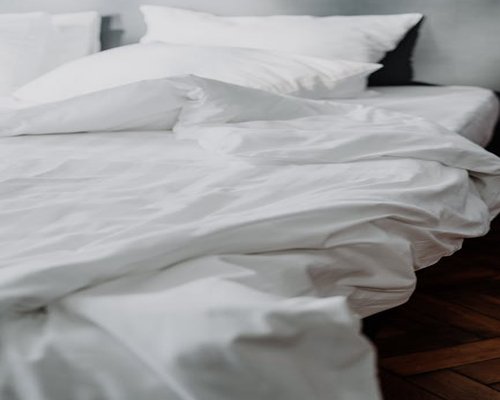 Soft light entering a quiet bedroom with neatly organized linen expressing optimal sleep hygiene conditions